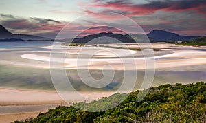 Pink clouds at sunrise over Hill Inlet at Whitsunday Island in rare green color