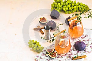 Pink cocktail with fig, thyme, cinnamon and grapes in glass on pink concrete background, close up. Autumn drinks and alcoholic
