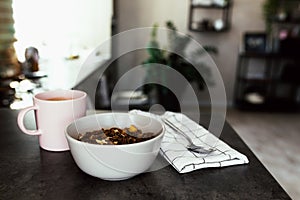 Pink coffee cup, chopped fruits in bowl blueberries, spoon on towel in kitchen