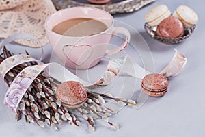 Pink coffee mug with sweet pastel french macaroons and wil