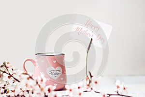 Pink coffee mug, white cherry flowers and ``Happy Mother`s Day`` note