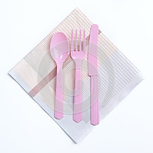 Pink color plastic fork, spoon and knife on napkin