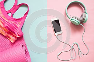 Pink color sport bra and yoga mat with smartphone and earphones