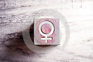 Pink Colored Gender Sign For Female On A Wooden Block On A Table