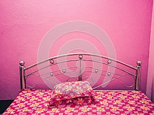 Pink coloured bed with floral bed sheet with pink walls