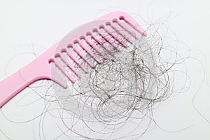 Pink comb with lots of hair fall on white background.