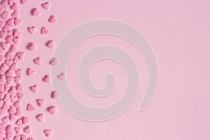 Pink confectionery hearts located on left side on pink background, greeting card, copy space