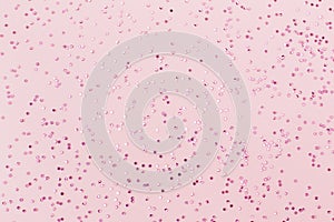 Pink confetti on pastel pink paper background. Festive holiday backdrop. Birthday congratulations Christmas New Year.