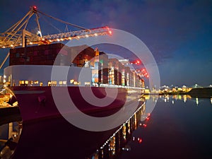 Pink container ship at night at Southampton Docks UK aerial side view