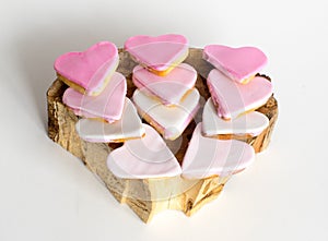 Pink cookies on the wooden old tree cut, heart shape, white background