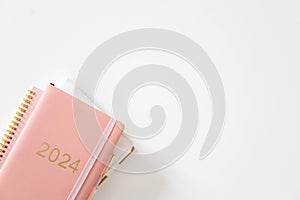 Pink coral colored diary for the year 2024 and many other diaries, pen, white background