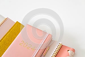 Pink coral colored diary for the year 2024 and many other diaries, pen, white background