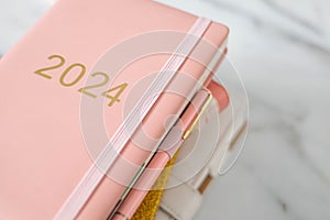 Pink coral colored diary for the year 2024, pen, marble background