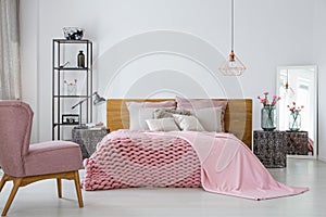 Pink cozy blanket and duvet on king size bed in contemporary bedroom interior, copy space on empty white wall