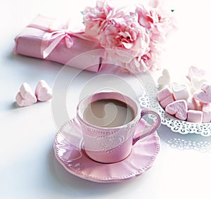 Pink cup with coffee, marshmallows hearts, gift and bouquet of pink roses