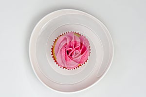 Pink cupcake on a plate isolated on white background. Delicious cake. Top view