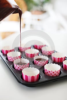 Pink Cupcake Wrappers Being Filled with Dough for Chocolate Cupcakes