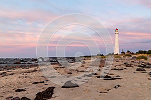 Pink dawn near lighthouse on the shore.