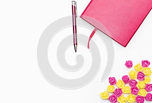 Pink diary with a pen and small yellow pink roses on a white background