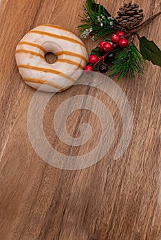 Pink Donut in glaze and festive pine branch on wooden natural background