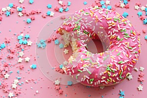 Pink donut surrounded By sugar filling for cake, frame on pink background, Free space for text.