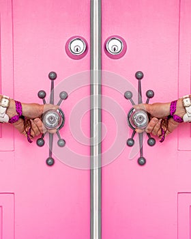 Pink door with a woman's hands holding doorknobs photo