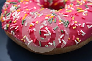 Pink doughnut with colored sprinkles on a blue plate