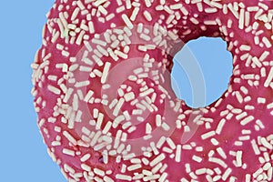 Pink doughnut with sprinkles on pastel blue background. Sugar, sweets, snack, junk food concept. Top view. Space for