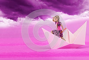 Sogni rosa bambina di vela su barca di carta sotto il cielo viola.