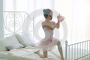 Pink dresses little girl 9 year dancing ballet with white bed in bedroom at home, Ballerina young girl practicing ballet