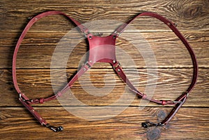 Pink dual camera harness, multi-camera strap harness, leather camera strap on brown wooden background.