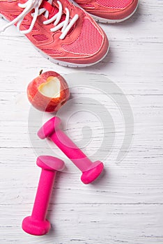 Pink dumbbells, training shoes and apple with heart, fitness concept, healthy lifestyle, top view