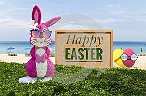 Pink Easter bunny and Easter egg with cardboard sign on tropical beach