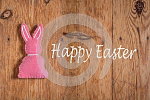 Pink Easter bunny with text `happy Eastern` on a wooden background