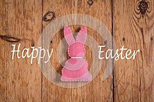 Pink Easter bunny with text `happy Eastern` on a wooden background