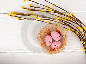 pink Easter eggs in nest on white wooden background, copy space