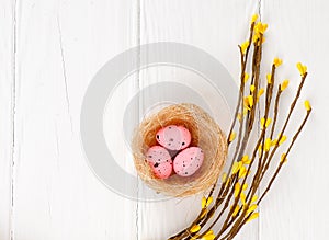 pink Easter eggs in nest on white wooden background, copy space