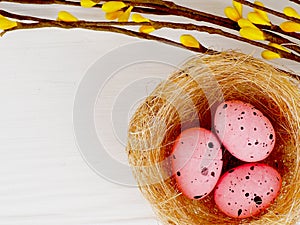 pink Easter eggs in nest on white wooden background, copy space