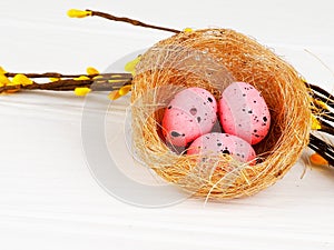 pink Easter eggs in nest on white wooden background, copy space