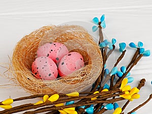 pink Easter eggs in nest on white wooden background, copy space