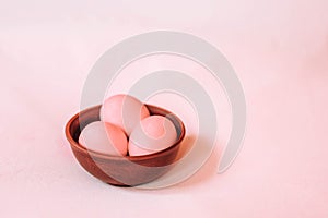 Pink Easter eggs on a wooden plate on a pink background. Easter concept.