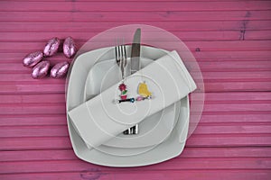 Pink Easter time table place setting in white with chocolate wrapped eggs and decorations