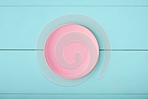 Pink empty plate on turquoise wooden table.