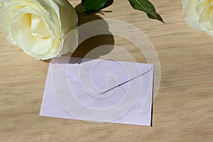 Pink envelope letter and white rose flower on wood table with sunlight