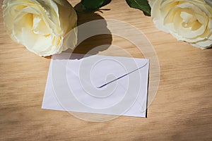 Pink envelope letter and white rose flower on wood table with sunlight