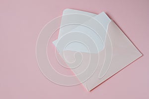 Pink envelope with white blank paper isolated on a pastel pink background