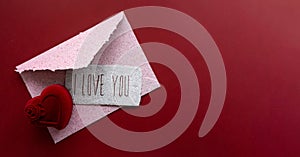 Pink envelope, white congratulation card and ring case on a red background. Valentine day card