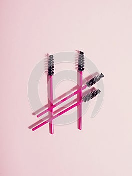 Pink eyelash brushes on a pink background with copyspace