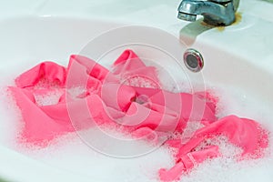 The pink fabric was soaked in detergent water at the sink