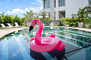 A pink flamingo pool float is floating in a pool